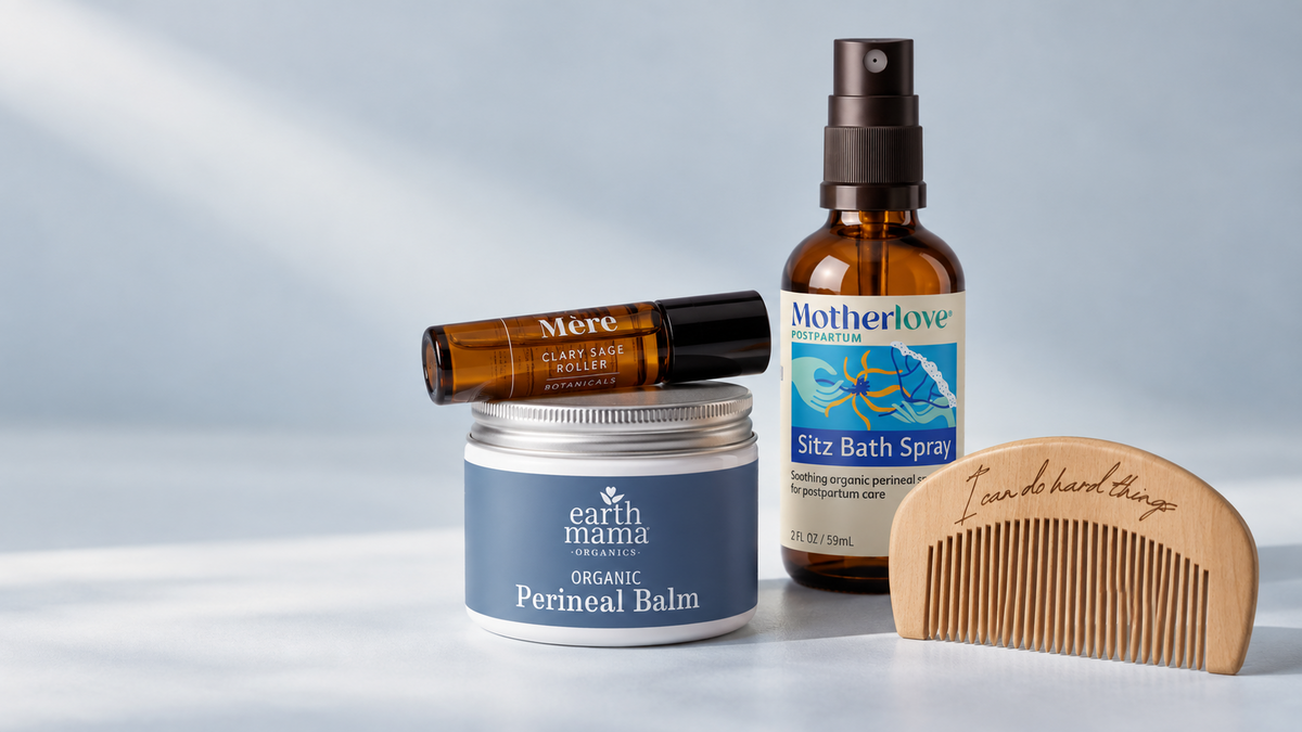 Motherhood care essentials with a clary sage roller, sitz bath spray, perineal balm and wooden labor comb on a blue background